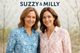 Twee vrouwelijke modellen van ongeveer 40 jaar oud in een lichtblauwe bloemenblouse en een wit-roze bloesemblouse van Suzzy & Milly met frisse uitstraling en bold merknaam